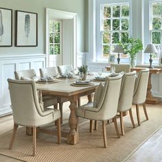 a dining room table and chairs in front of windows with pictures on the wall behind them