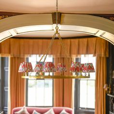 a chandelier hanging from the ceiling in a living room with red couches