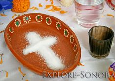 an orange bowl filled with white powder next to a cup and some glasses on a table