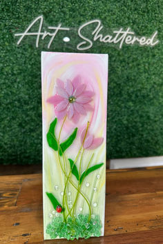 a card with pink flowers on it sitting on a wooden table next to a green wall