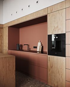 a kitchen with pink walls and wooden cabinets