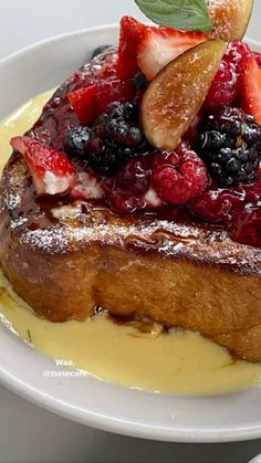 a white plate topped with french toast covered in fruit