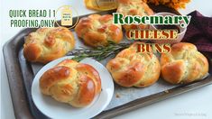 some bread rolls are on a tray with butter and rosemary sprigs next to them