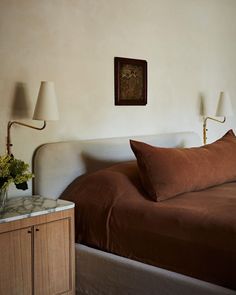 a bed with two lamps on either side of it and a night stand next to it