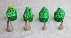 four cupcakes with green frosting and trees on top are lined up next to each other