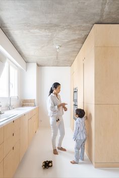 a woman standing next to a child in a kitchen