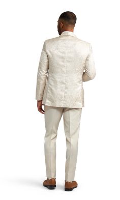 A slim ivory paisley tuxedo coat with one button and a shawl lapel. Formal Fitted Cream Outerwear, Cream Fitted Formal Outerwear, Cream Fitted Outerwear For Formal Occasions, Elegant Fitted Nehru Jacket For Groom, Cream Long Sleeve Tuxedo For Formal Occasions, Elegant Beige Nehru Jacket With Long Sleeves, Classic Fitted Nehru Jacket For Wedding, Elegant Tailored Nehru Jacket For Groom, Tailored Elegant Nehru Jacket For Wedding