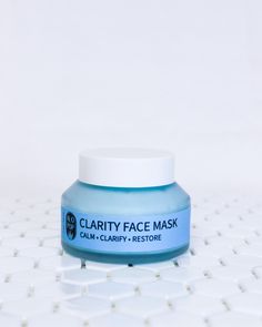 Blue clarity clay face mask in a glass jar with a white screw top lid. This gentle face mask is sitting on white geometric tiles with a white background behind it. The acne friendly mask has a blue label with black text. Congested Skin, Bentonite Clay, Grapefruit Essential Oil, Facial Moisturizer, Vegetable Glycerin, Facial Moisturizers, Green Tea Extract, Tree Oil, Skin Healing