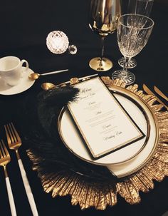 a table setting with black and gold place settings