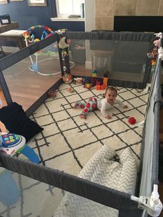 a baby in a playpen with toys on the floor