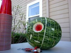 a large watermelon sitting on top of a table in front of a house