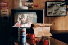 a can of pepsi sitting on top of a wooden table next to a television set