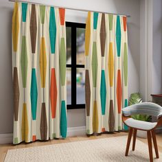 a living room with a chair, window and rug in front of the curtains that have colorful shapes on them