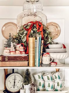 a shelf filled with christmas decorations and books on top of each other in front of a clock