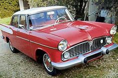 an old red and white car is parked in the driveway