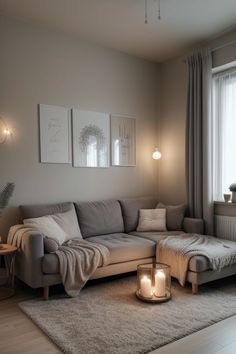 a living room with a couch, chair and candles on the floor in front of a window