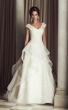 a woman in a white wedding dress standing on a checkered floor with columns and curtains behind her