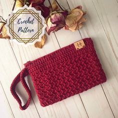 a red crocheted purse sitting on top of a white wooden floor next to dried leaves