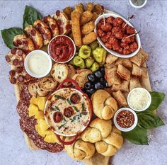 a wooden platter filled with different types of appetizers and dipping sauces