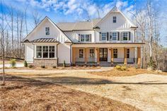 a large white house with lots of windows in the front yard and trees around it