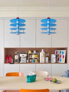 an image of a kitchen setting with blue lights hanging from the ceiling and orange chairs