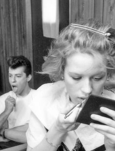 black and white photograph of two people sitting at a table with an electronic device in front of them