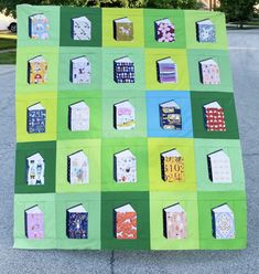 a green and blue patchwork quilt with houses on it's sides, in the middle of a parking lot