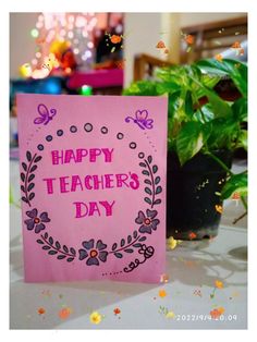 a pink card with the words happy teachers day on it sitting next to potted plants