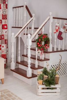 a living room filled with furniture and christmas decorations on the wall next to a stair case