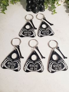 six keychains with the words ride or die on them are sitting next to a plant