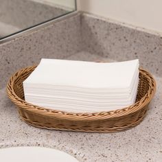 a wicker basket with folded napkins in it on a bathroom countertop next to a mirror