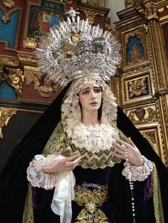 a woman dressed in black and gold standing next to a statue