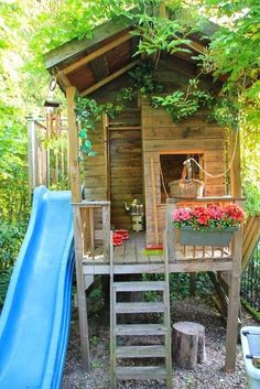 there is a small wooden house with a slide in the yard and flowers growing on it