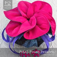 a pink flower with purple and blue ribbons on it's headbands sitting on top of a lace doily