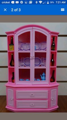 a pink china cabinet with glass doors and drawers on the bottom shelf is filled with dishes