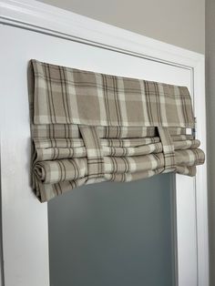 a window with a checkered valance hanging from it's side, in front of a white door