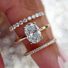 a woman's hand with three different rings and one diamond ring on her finger