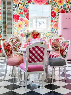 a dining room with floral wallpaper and pink refrigerator in the corner, next to checkered flooring