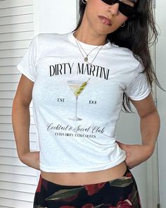 Dirty Martini Social Club Baby Tee, Martini Coquette Shirt, Extra Dirty Shirt, Vintage Tee, Y2K tee, Cocktail Tshirt, Martini Top, Tini Time *IMPORTANT PLEASE READ BEFORE PURCHASING* My store uses DTG (Direct to Garment) printing. This means the design is printed into the garment. This means it is designed to last longer than other printing processes. Due to this printing process the design colors may not be as vibrant as shown in the photos. There may at times be a slight difference between rea Fitted White T-shirt With Text Print, Fitted Basic T-shirt With Funny Print, Fitted White Graphic Tee, Fitted White Screen Print T-shirt, Fitted White T-shirt With Screen Print, Fitted Short Sleeve Top With Screen Print, Fitted Short Sleeve Tops With Text Print, Fitted Summer T-shirt With Letter Print, Fitted Short Sleeve Graphic Tee Shirt