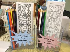 two clear vases with colored pencils and coloring bookmarks in them on a table