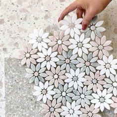 a person holding onto a paper plate with flowers on the surface in front of them