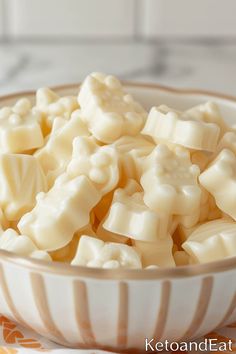 a bowl filled with white chocolate pieces on top of a marble countertop next to an orange and white towel