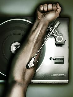 a hand holding up a record player with his arm