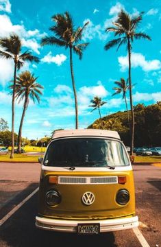 an old vw bus is parked in a parking lot with palm trees behind it