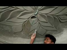 a man is working on a large flower wall decoration in the shape of a leaf