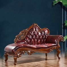 a red leather couch sitting on top of a hard wood floor next to a plant