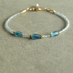 This dainty bracelet has three beautiful rare blue aquamarine oval nuggets at its center, framed by tiny light aquamarine stones and gold beads.  This March birthstone women's jewelry bracelet closes with a 14K gold filled lobster clasp, and has a freshwater pearl at the closure. The color of the gorgeous natural aquamarine ovals is hard to describe and to photograph -- a rare rich medium blue aquamarine tone that is one of the sweetest blues I've seen.  With the gold beads, and tiny very light Etsy Wishlist, Aquamarine Bracelet, Aquamarine Beads, Dainty Bracelet, Aquamarine Jewelry, Natural Stone Jewelry, March Birthstone, Aquamarine Stone, Dainty Bracelets