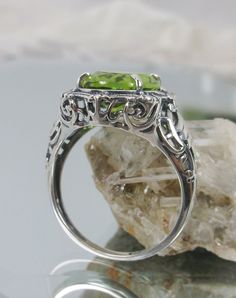 "Natural Green Peridot Ring Description Beauty Design#229 MADE To ORDER This is a brand new stunning Art Nouveau/Victorian reproduction sterling silver filigree ring. The oval-cut high-quality natural peridot is 12mm by 10mm (just shy of 3/8\" inch) in dimension... The ring is 5/8th of an inch (16.5mm) NS (long) on the finger. The ring and gem sit 7mm off the finger. The inside of the band is marked 925 for sterling. Notice the beautiful filigree swirl like the craftsmanship of the silver settin Unique Luxury Peridot Rings, Art Deco Oval Filigree Ring With Gemstone, Classic Peridot Jewelry With Halo Setting, Oval Gemstone Filigree Ring In Art Deco Style, Oval Peridot Rings With Accent Stones, Oval Filigree Ring With Center Stone, Oval Filigree Ring With Accent Stones For Promise, Oval Rings With Intricate Art Deco Design, Art Deco Oval Rings With Intricate Design