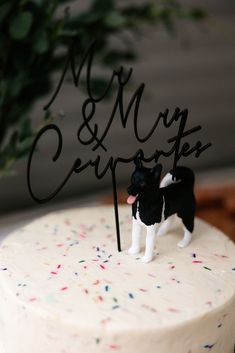 a small black and white dog figurine on top of a frosted cake