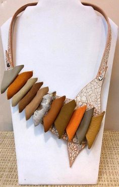 Our Color Track Bib Necklace hand crafted featuring different colorful leather shaped rolled shapes on a white crackled piece of leather. A unique handmade one of a kind piece of jewelry designed and created by artist Nansea Taylor from Seas Creations on Cape Cod. Made in USA Handmade White Leather Jewelry, Unique Leather Necklace, Beige Leather Jewelry, Old Cape Cod, Unusual Necklace, Queen Jewelry, African Queen, Colored Leather, Bib Necklace